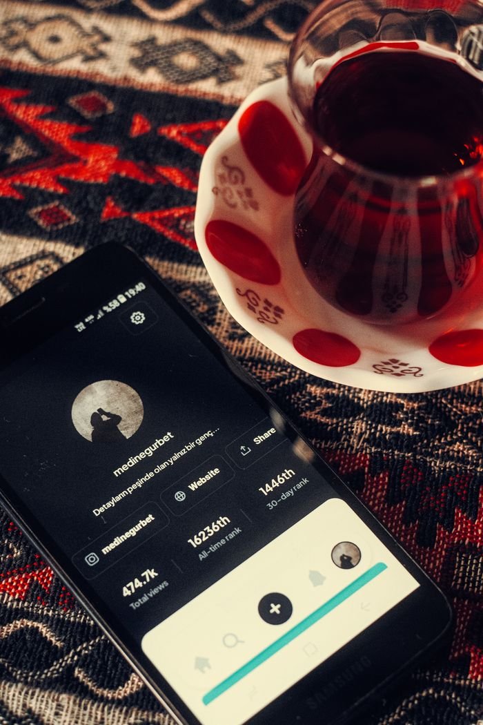 gallery-6 Overhead view of a vintage cup of tea next to a smartphone on a patterned surface, creating a cozy atmosphere.