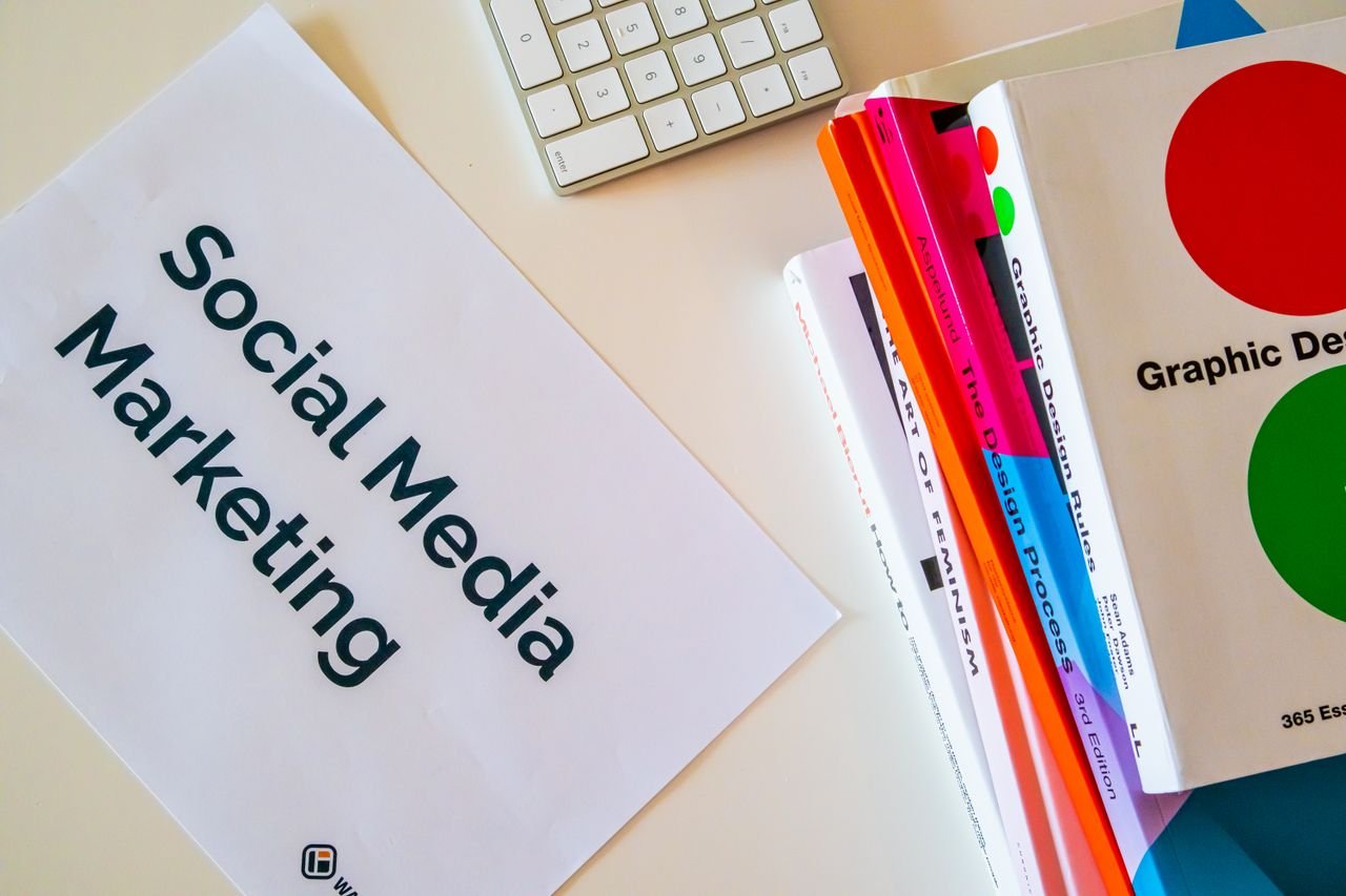 our-services-1 A top view of social media marketing text alongside graphic design books and a keyboard.