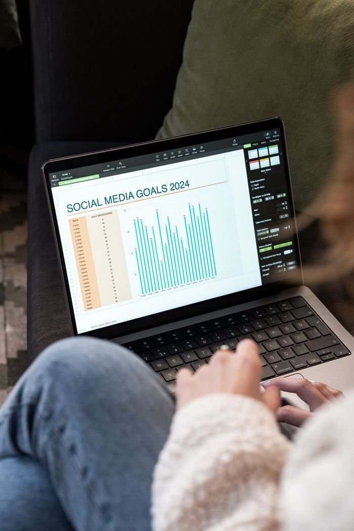 our-services-1 Woman reviewing 2024 social media goals chart on laptop indoors.